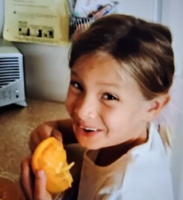 The spokesperson smiling and holding an orange